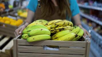 a woman holding a crate of bananas in a grocery store video