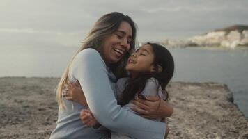 a woman and her daughter are hugging on the beach video