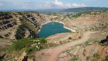 aéreo topo Visão em aberto mineração pedreira com inundado fundo, turquesa superfície do a lago. pedreira lagoa cheio com verde plantas e Claro turquesa água video