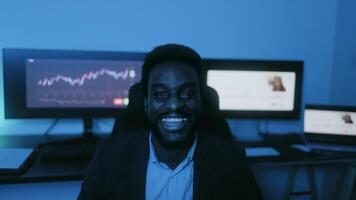 un hombre sonriente en frente de Tres computadora monitores video