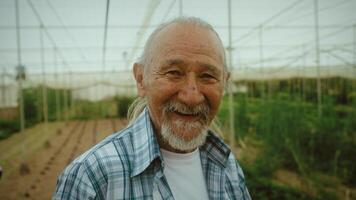 an older man smiles in a greenhouse video