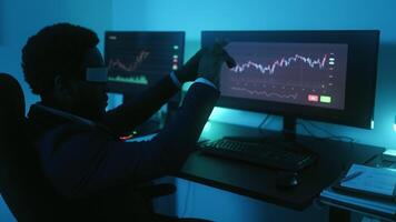 a man wearing a vr glass is sitting at a desk with two monitors video