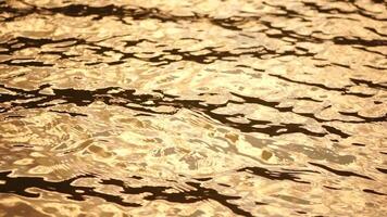 Sun reflecting on sparkling sea lake water surface, ocean at sunset, sunrise. Sunrays flickering in Ripples on water surface. Golden shimmering sea waves in sun. Slow motion. Abstract nautical nature video