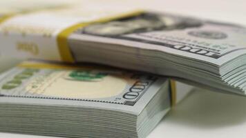 stack of bank bundles with US dollars on a white background. Close-up shot of new, freshly printed hundred-dollar bills rotating on a table. cash flow, business investment, or big money concepts. video