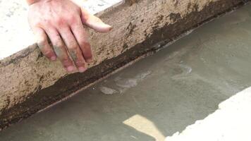 Construction, Worker Hands smooth wet cement in wooden frame at a construction site during daytime to ensure an even surface video