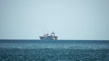 Fishing boat trawler catches fish while sailing on sea. A commercial fishing boat on the horizon in a distance sail to catch school of fish on calm sea surface in summer. Commercial catch of sea fish. video