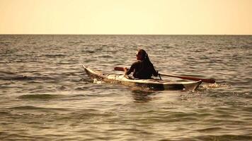 donna mare kayak. contento sorridente donna nel kayak su oceano, paddling con di legno remo. calma mare acqua e orizzonte nel sfondo. attivo stile di vita a mare. estate vacanza. video