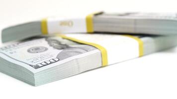 stack of bank bundles with US dollars on a white background. Close-up shot of new, freshly printed hundred-dollar bills rotating on a table. cash flow, business investment, or big money concepts. video