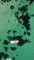 aereo verticale Visualizza di paesaggio marino con cristallo chiaro azzurro mare e roccioso sponde. yachts nel un' bellissimo laguna su fondale di rocce. il concetto di un ideale destinazione per estate viaggio e vacanza. video