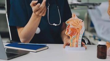 asian female doctor wearing face mask is showing a rectal model and explaining to elder senior man patient in hospital video