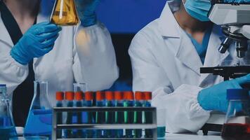 Young scientists conducting research investigations in a medical laboratory, a researcher in the foreground is using a microscope video