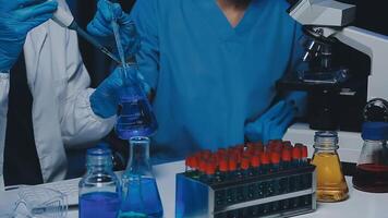 Young scientists conducting research investigations in a medical laboratory, a researcher in the foreground is using a microscope video