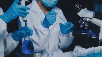 Young scientists conducting research investigations in a medical laboratory, a researcher in the foreground is using a microscope video