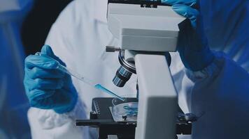 Young scientists conducting research investigations in a medical laboratory, a researcher in the foreground is using a microscope video