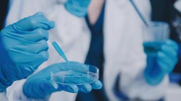 Young scientists conducting research investigations in a medical laboratory, a researcher in the foreground is using a microscope video