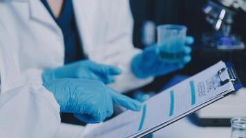 Young scientists conducting research investigations in a medical laboratory, a researcher in the foreground is using a microscope video