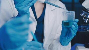 Young scientists conducting research investigations in a medical laboratory, a researcher in the foreground is using a microscope video