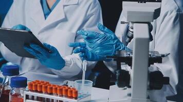 Young scientists conducting research investigations in a medical laboratory, a researcher in the foreground is using a microscope video