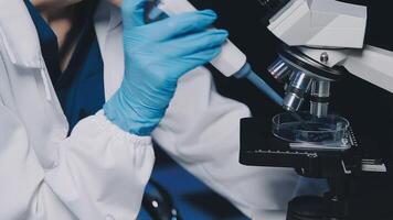 Young scientists conducting research investigations in a medical laboratory, a researcher in the foreground is using a microscope video