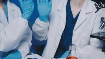 Young scientists conducting research investigations in a medical laboratory, a researcher in the foreground is using a microscope video