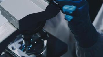 Young scientists conducting research investigations in a medical laboratory, a researcher in the foreground is using a microscope video