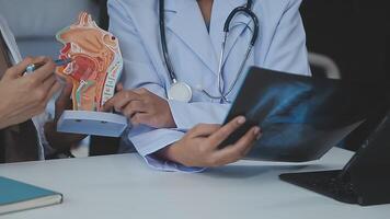 groupe de médecins avec portable ordinateur et presse-papiers avec les documents réunion et discuter à médical bureau. infirmière en présentant symptômes de maladie, collègues prise Remarques pendant réflexion. video