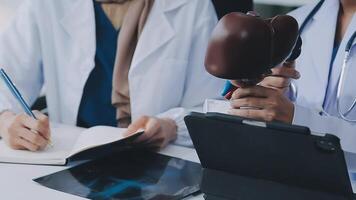 grupo de doctores con ordenador portátil computadora y portapapeles con documentos reunión y que se discute a médico oficina. enfermero presentación síntomas de enfermedad, colegas tomando notas durante lluvia de ideas. video