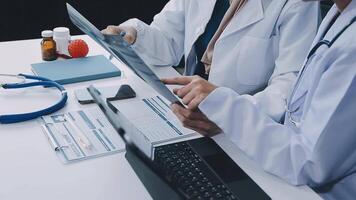 Group of doctors with laptop computer and clipboard with documents meeting and discussing at medical office. Nurse presenting symptoms of disease, colleagues taking notes during brainstorming. video