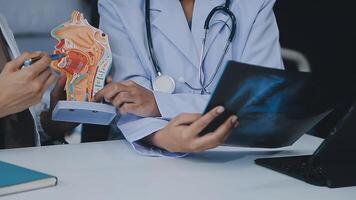 groupe de médecins avec portable ordinateur et presse-papiers avec les documents réunion et discuter à médical bureau. infirmière en présentant symptômes de maladie, collègues prise Remarques pendant réflexion. video