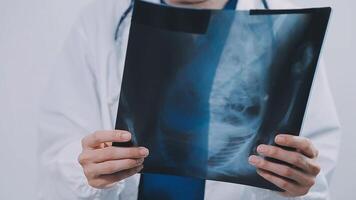 calificado mujer médico en blanco uniforme comprobación radiografía película, diagnosticar paciente lesión, sonriente calma y en pie aislado en estudio antecedentes con Copiar espacio. cuidado de la salud y médico seguro concepto video