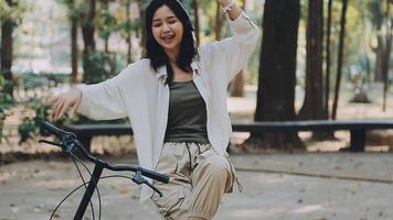 atractivo joven mujer en un sombrero montando un bicicleta en un parque. activo gente. al aire libre video