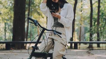 attraktiv ung kvinna i en hatt ridning en cykel i en parkera. aktiva människor. utomhus video