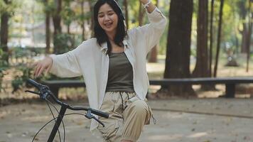 atractivo joven mujer en un sombrero montando un bicicleta en un parque. activo gente. al aire libre video