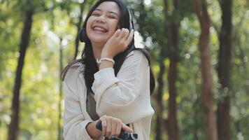 Attractive young woman in a hat riding a bicycle in a park. Active people. Outdoors video