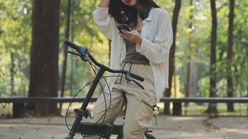 atractivo joven mujer en un sombrero montando un bicicleta en un parque. activo gente. al aire libre video