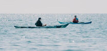 Man woman sea kayak. Happy free man and woman in kayak on ocean, paddling with wooden oar. Calm sea water and horizon in background. Active lifestyle at sea. Summer vacation. photo