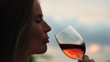 magnifique femme les boissons rouge du vin de une verre à le coucher du soleil dans le vignoble. une femme main secoue une verre de rouge du vin légèrement. du vin dégustation et du vin fabrication concept. lent mouvement video