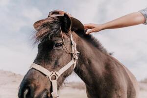 joven contento mujer con su poni caballo en noche puesta de sol ligero. al aire libre fotografía con Moda modelo muchacha. estilo de vida humor. concepto de al aire libre equitación, Deportes y recreación. foto