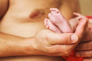 Father holding newborn baby feet on his hands photo