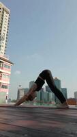 Woman practice yoga at the rooftop of the skyscraper in a big city. video