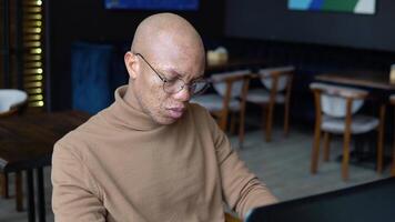 African american man with freckles on his face types text on a laptop keyboard. Close-up view of hands video