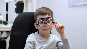 A caucasian boy in a trial frame for the selection of contact lenses at an appointment with an ophthalmologist video