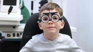 een jongen in een beproeving kader voor lens selectie is zittend in een oogheelkunde kliniek video