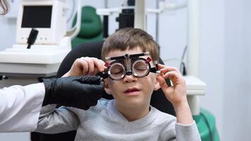 The ophthalmologist makes adjustments to the trial frame to select lenses for the caucasian boy video