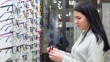 jovem mulher inspeciona óculos dentro a óptica loja video