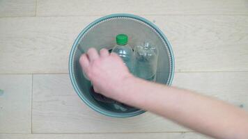 en mannens hand tar vänder plockning upp fem plast flaskor av annorlunda färger och volymer från de kontor skräp burk. sopor sortering. plast återvinning video
