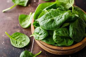 AI generated Fresh spinach leaves in bowl on rustic wooden table photo