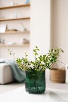 Glass green vase with branches in modern living room decor in light colors. Elegant lifestyle Scandinavian scene photo