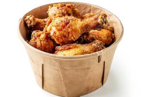 AI generated Collection of golden brown and crispy roasted Fried chicken served on a brown paper bucket isoalted on white background. photo