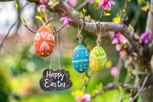 AI generated Colorful Easter eggs hanging on blooming tree branches outdoor in garden. photo